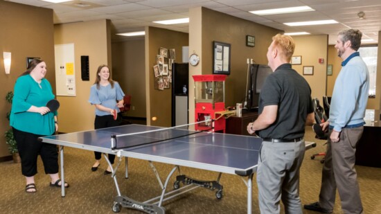 1st Service Solutions employees playing ping pong. The company has a fun and very relaxed work atmosphere. Ping pong is played almost every day.