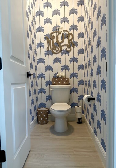Coastal-themed wCoastal-themed wallpaper and wood-toned flooring from a bathroom remodel by Patty Morton.