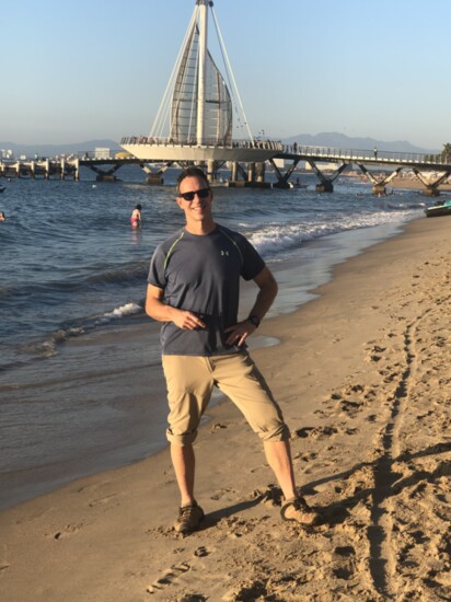 Jim Miller on the beach in Puerto Vallarta with the Muelle de Playa Los Muertos behind him (Photo by Susan Grossman)