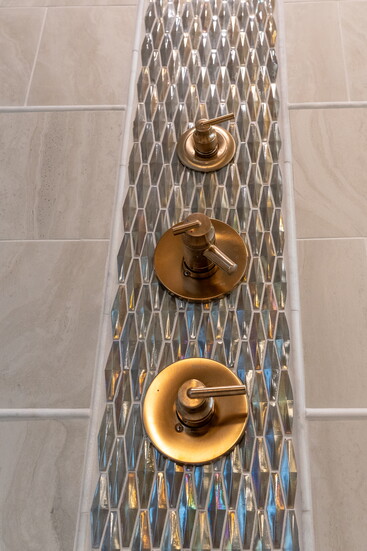 This prismed iridescent jeweled tile was the perfect waterfall accent for the satin brass controls.