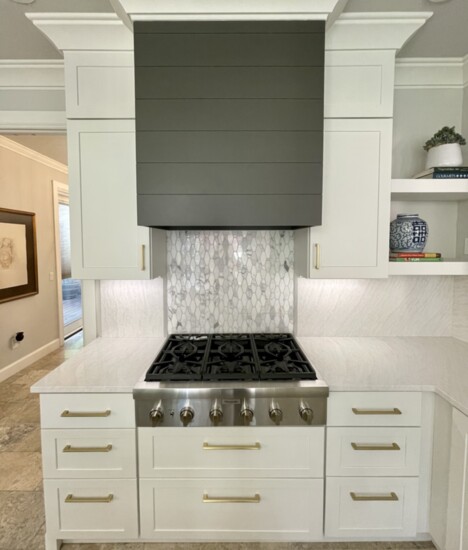 The white Shaker-style cabinets represent an elegant transitional style juxtaposed against the dark, Urban Bronze island and hood.