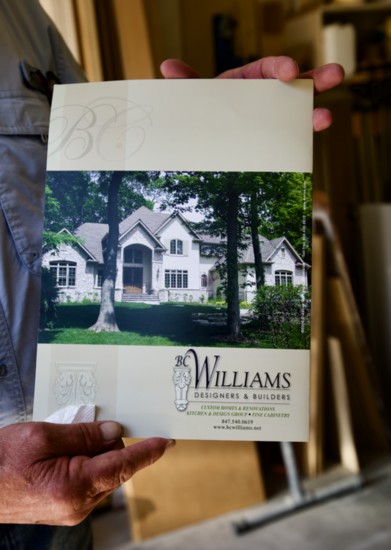 Williams holds a brochure featuring a custom build he completed in Long Grove.