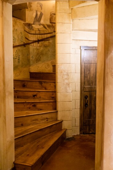 A winding staircase leads to the basement, crafted to mimic a 17th-century Burgundy wine cellar.