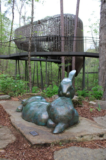 A bronze rabbit statue in front of the treehouse inside Garvan Woodland Gardens.