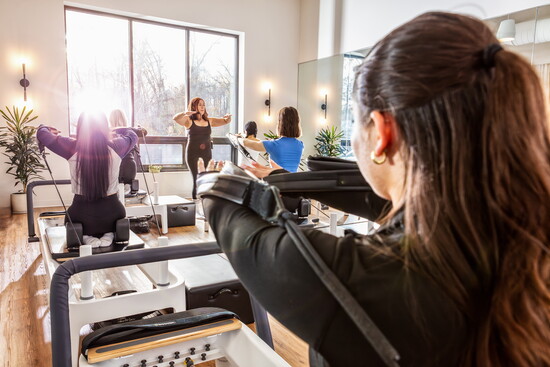 Class attendees focus on slow and controlled movements during a Pilates Reformer class