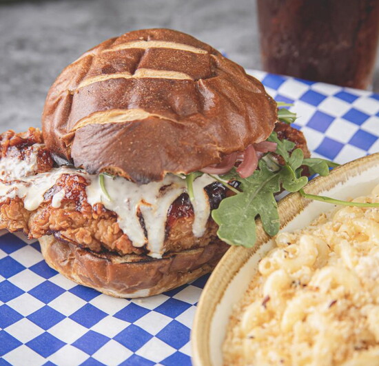 Honor Café – Signature fried chicken sandwich with creamy sauce, pickled cucumbers, and mac and cheese.
