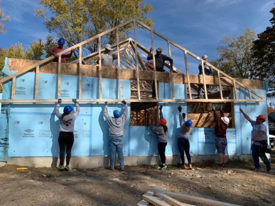 Volunteers work together to raise roof trusses while building a Habitat CFC home.