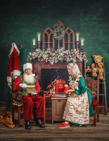 Santa examines his list as Mrs. Claus watches.