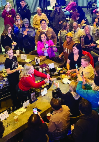 Guests gather around the bar as sports broadcaster Holly Rowe, center, serves drinks.