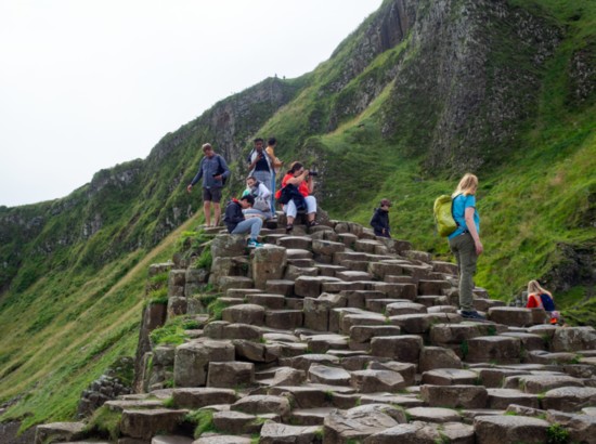 Visitors on Giant’s Causeway, a unique hexagonal geological formation of volcanic basalt rocks and popular tourist attraction.