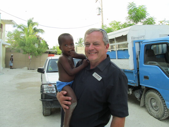 Agape Flights CEO Allen Speers shares a quiet moment with a young child during a mission visit to Haiti.