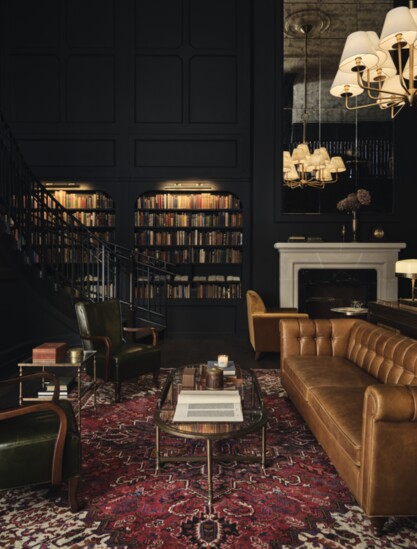 With two wrap-around staircases, the Library welcomes guests to comfortably gather among book-lined walls, Chesterfield sofas, and wingback chairs.