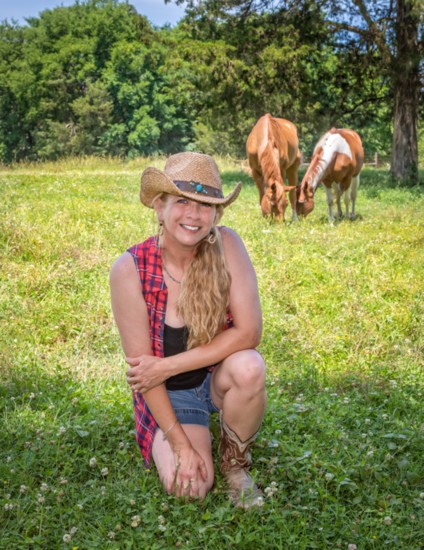 Rachel McAuley poses with two of her rescue horses, Saint and Country, in the background.