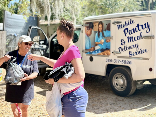 Bridge of Hope driver Susan Boyd hands food to a patron.