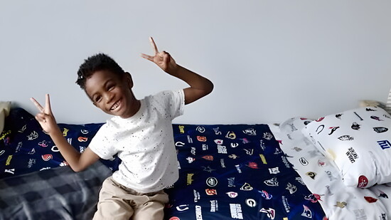 Boy shows peace signs in his new Sleep in Heavenly Peace bed.