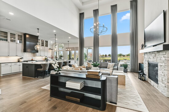 A bold statement in the family room with dramatic stone fireplace, towering windows, and modern chandelier. This space offers the perfect balance of comfort and