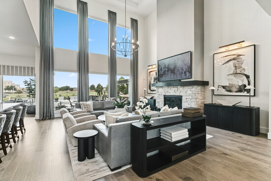 A bold statement in the family room with dramatic stone fireplace, towering windows, and modern chandelier. This space offers the perfect balance of comfort and