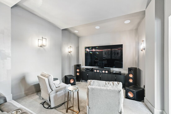The media room delivers a true cinematic experience with surround sound, recessed lighting, and space for reclining seating.