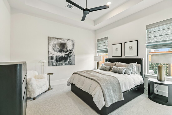 This guest suite with neutral tones, tray ceilings, and abundant natural light is a restful retreat. Bedroom 2 downstairs.