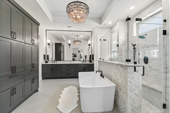 The spa-inspired primary bath offers dual vanities, a freestanding soaking tub, and a walk-in shower framed in marble tile.