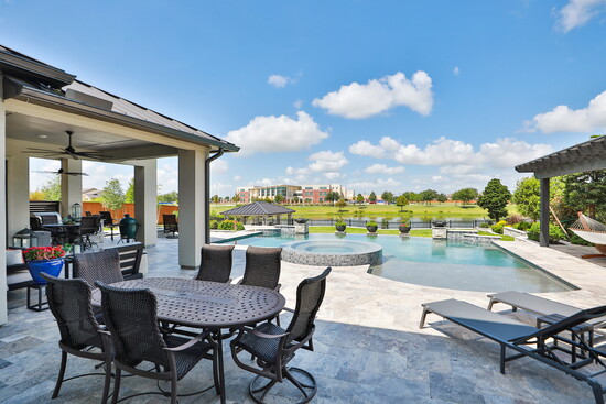  Backyard oasis–the shimmering pool, elevated spa, outdoor lounge, and private dock all framed by lush green lawn.