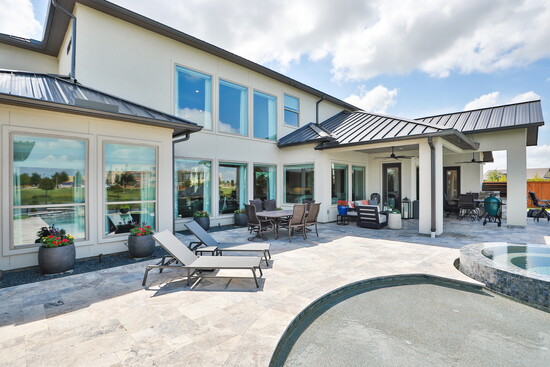 A covered patio and pergola extend the outdoor living areas, creating a seamless flow for gatherings.