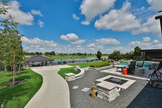  Backyard oasis–the shimmering pool, elevated spa, outdoor lounge, and private dock all framed by lush green lawn.
