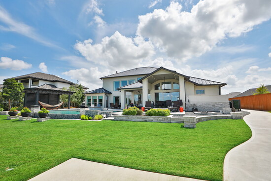  Backyard oasis–the shimmering pool, elevated spa, outdoor lounge, and private dock all framed by lush green lawn.