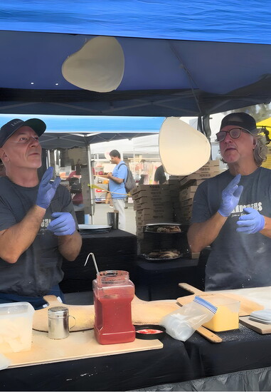 Kent Land and crew member Greg Byers take pizza-making to new heights, tossing homemade dough into the air. Photo Credit: Shelley Cartland