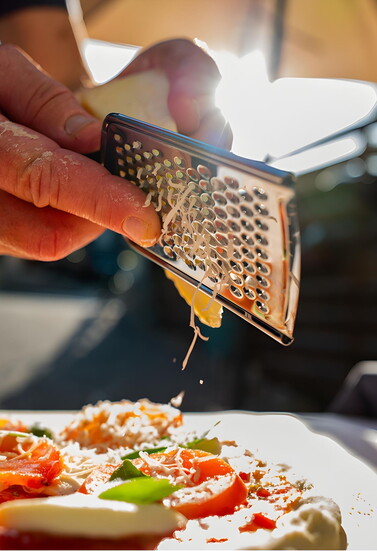 Adding Topping off a Classic Margherita pizza with freshly grated cheese. Photo Credit: Johnny Lorenz