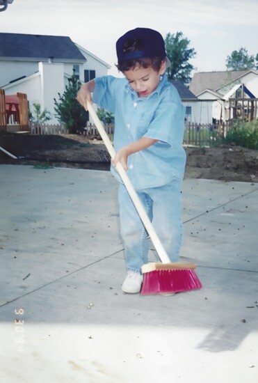 A young Alex Chekanoff sweeps debris off concrete.