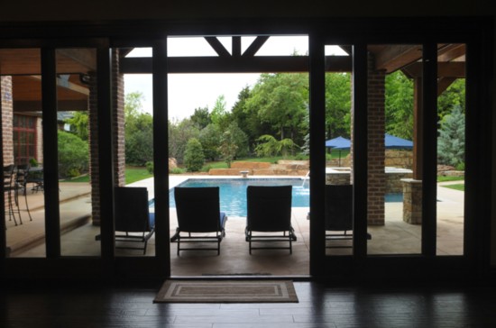 Large glass windows and doors allow for a view of the pool from inside the pool house.