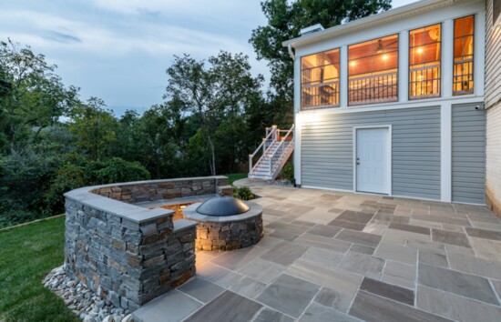 Flagstone covered lower patio with lit seating walls and a wood burning fire pit.