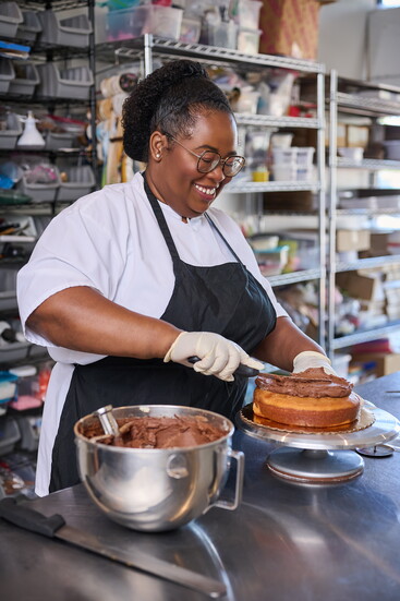Shellane begins to ice a yellow cake with her chocolate buttercream.
