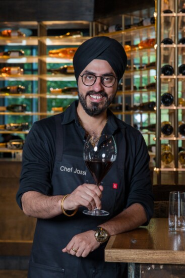 Chef Jassi in front of Amrina's impressive wine selection.