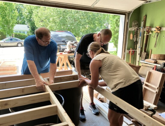 Vince Gullo (L), Jason McCauley (R) and Cathy McCauley (front) use a wooden spacer to ensure the correct sizing of a shelf that will hold glass canning jars.