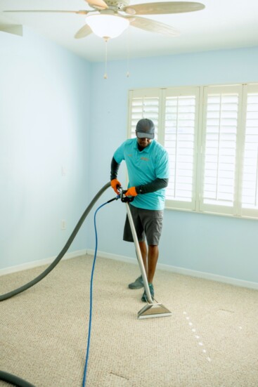 Chris Brown of TEAM US Carpet Care at work cleaning a house with wall-to-wall carpeting.