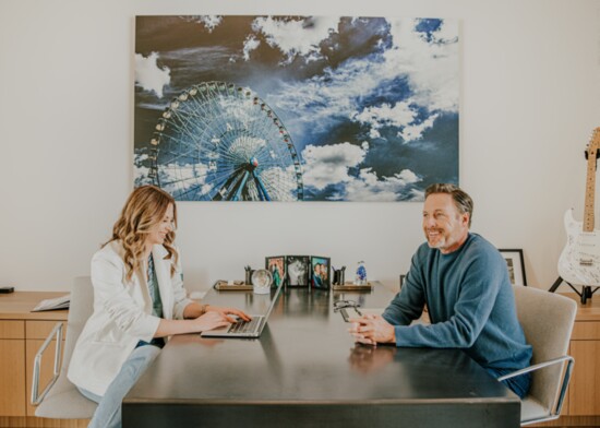 Lauren and Chris co-work and collaborate at their his & her desks with a Steve Wrubel photo brightening the wall.