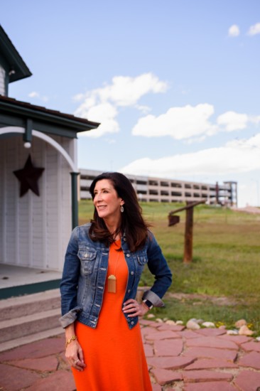 Lone Tree Mayor sits on the steps of a barn at the historic Schweiger Ranch in Lone Tree, with the newly oped RTD lightrail station in the background.