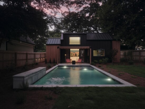 As dusk settles, a warm glow fills the interior, while the pergola can double as a structure for an outdoor projection screen.