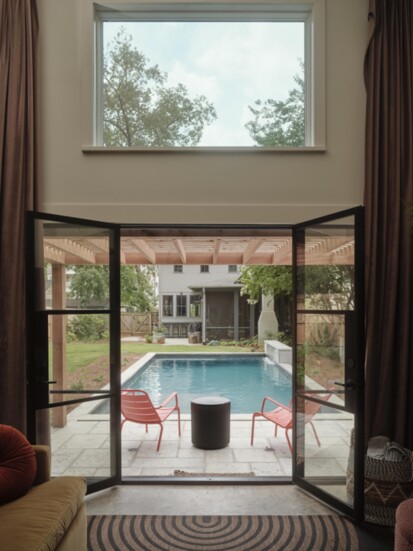 The view extends to the pool through the steel doors,, stretching towards the main house and its screen porch.