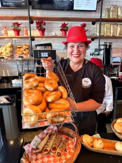 Julie Dragich, co-owner of The Bronx Bagel Buggy, welcomes guests with bagels, pastries, and other baked goods.