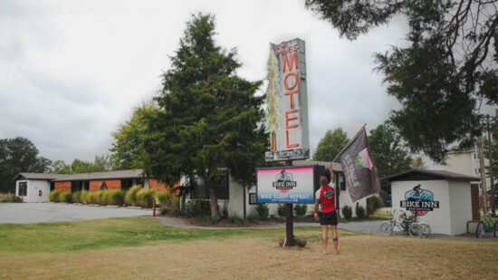 Rose hangs an Oz Trails flag from the 1951 Pines Motel sign 