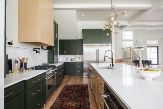 The kitchen features a massive marble-topped island, striking fixtures, a five-burner Bertazzoni gas range and side-by-side, full-size refrigeration station.