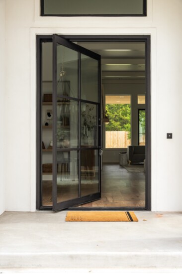 An 8-foot modern pivot door welcomes family and guests to this new home by Randolph Design + Build.
