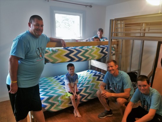 SHP volunteers present a new bunk bed to two deserving boys. Volunteers from left: Jim Watts, Eileen Watkins, Rick Duff and Thomas Watkins.