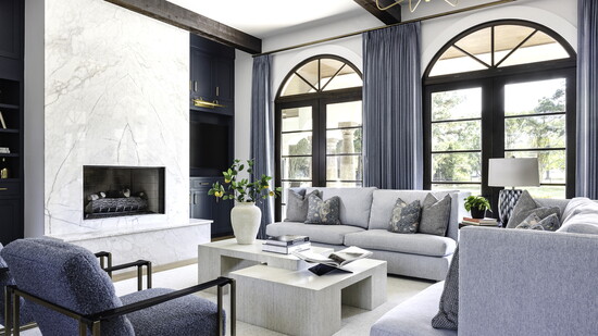 Huge windows fill this large living room with light. Chairma Design Group brought in cushy sofas and chairs and a beautiful chandelier.