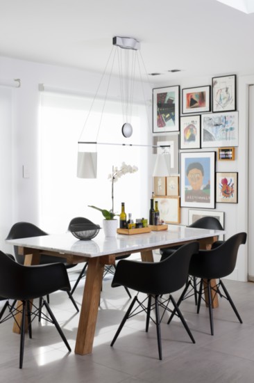 Designer Debora Kalkstein displays her kids’ artwork in her kitchen (even though her kids are now grown). Chairs by Vitra surround a marble-topped table
