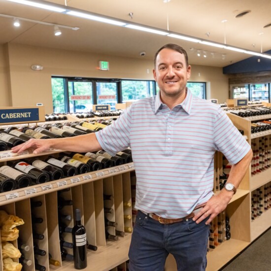 3rd generation owner Adam Sinks stands before some of his store's high end wine offerings.