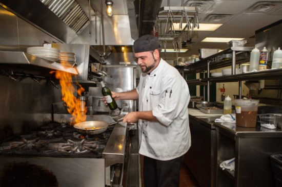 Chef JP adds white wine to the chicken in the pan